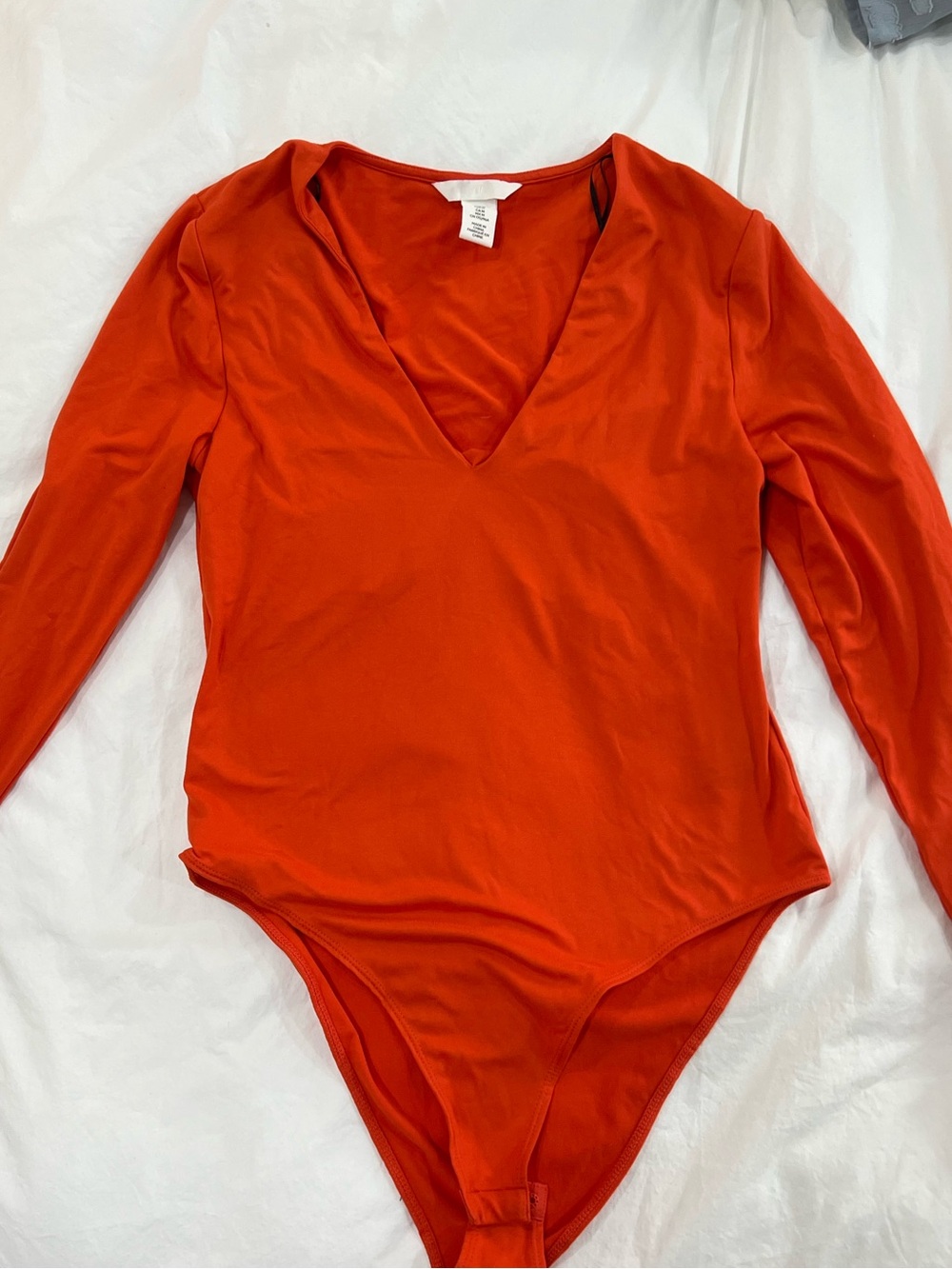 H&M orange bodysuit features long sleeves and a deep V-neckline